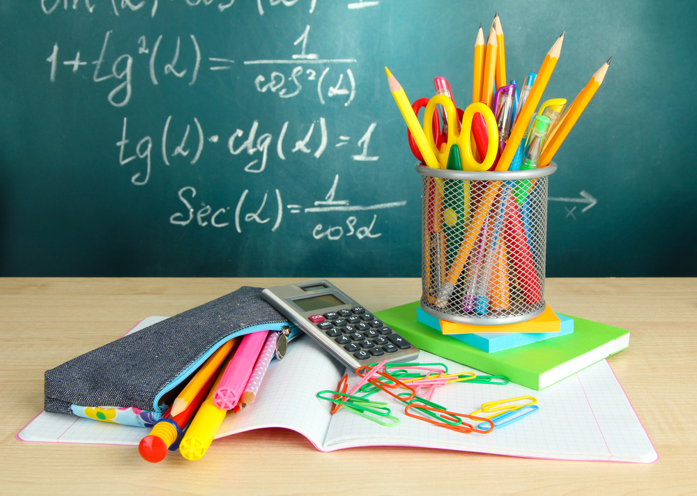 Back to school - blackboard with pencil-box and school equipment on table